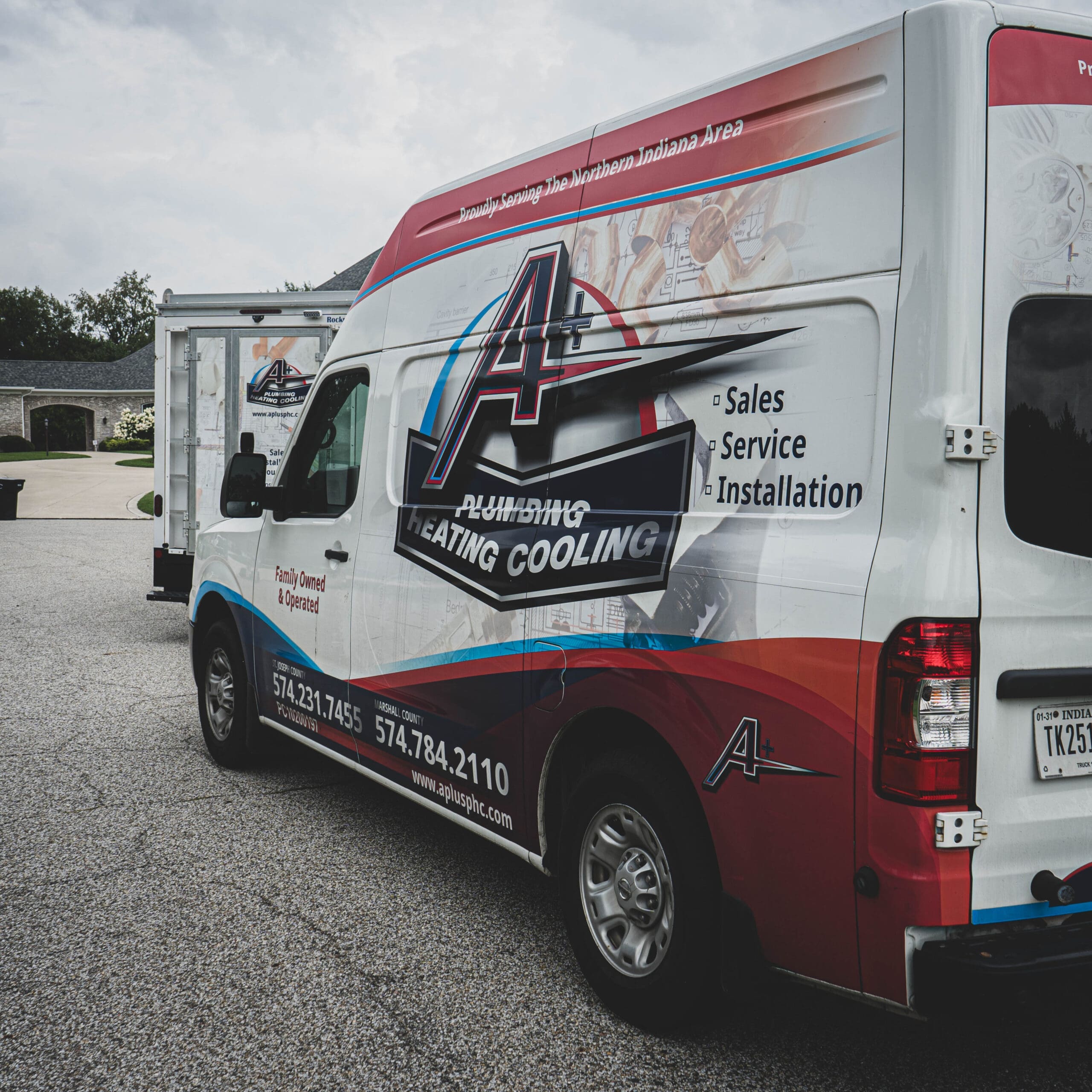 Service van for A+ Plumbing, Heating, and Cooling parked in a residential area